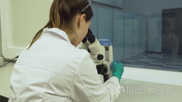 女生物学家在显微镜下看起来视频