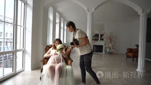 美丽的年轻怀孕女子当街摄影师及坐在椅子上在白色闲荡