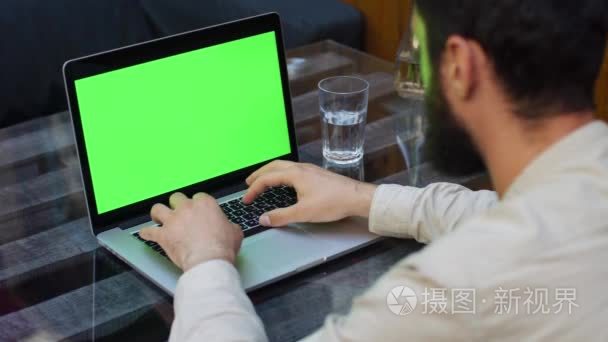 男人在与绿屏笔记本电脑上工作视频