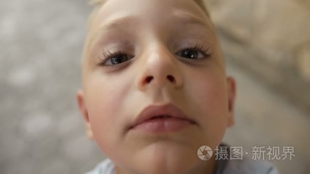 一个小男孩与美丽的黑眼睛和大眼睑亲吻摄像机目的。漂亮的小男孩