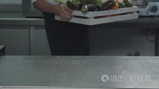 厨师在桌上放一盒蔬菜，蔬菜，蘑菇