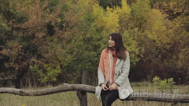 幸福的年轻女人，享受秋天坐在木栅栏上农村自然慢动作