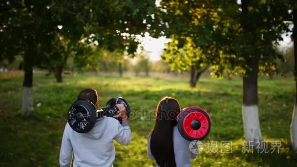 年轻的男人和女人骑在公园里飞。内容的技术。一个新的运动。关闭的双轮式自平衡电动滑板智能。电气机车在户外