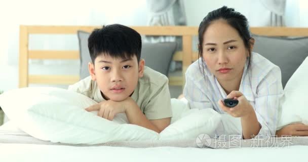 亚裔女子和亚洲男孩床上看电视视频
