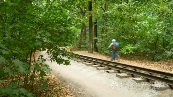 A lone cyclist drives along the path in the autumn forest along 