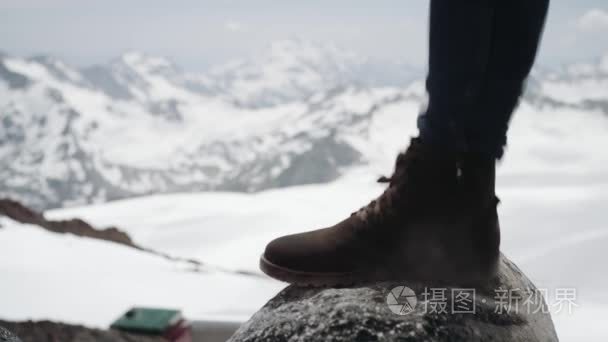 徒步登山者脚在踩在雪山风景秀丽的石头上