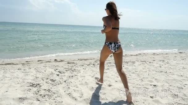 嬉戏在比基尼的女孩跑进海水域在沙滩上在夏天