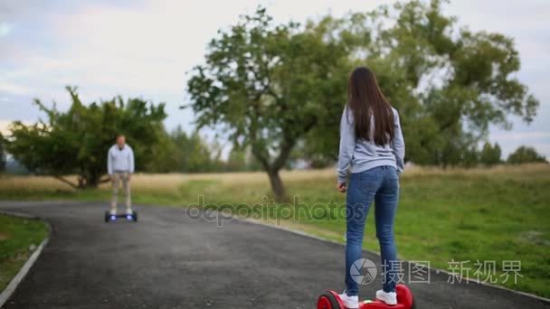 年轻的男人和女人骑在公园里飞。内容的技术。一个新的运动。关闭的双轮式自平衡电动滑板智能。电气机车在户外