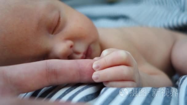 刚出生的婴儿睡觉保持妈妈的手指特写