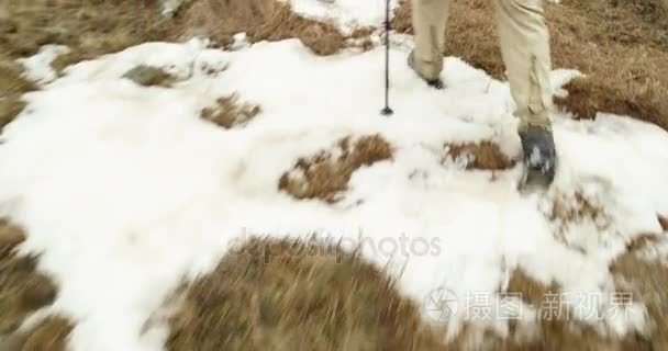 在多雪的线索路径上行走的背包徒步旅行者的男人。身后的腿细节。真正的背包客人成年后徒步旅行或在秋天或冬天在野生山户外徒步性质，多雾