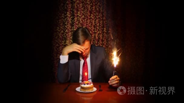 一个孤独的人庆祝的节日他独自坐在一张桌子一个蛋糕和一支蜡烛4k慢