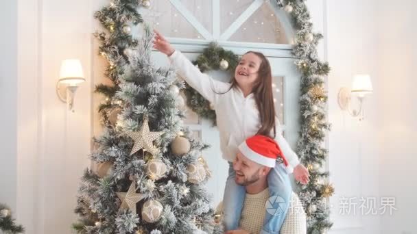 可爱的女孩和父亲在圣诞前夕装饰的冷杉树汁