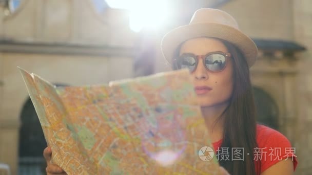 肖像拍摄的美丽的旅游妇女在太阳镜和帽子看旅游地图。女人旅行。老城市大厦背景。关闭