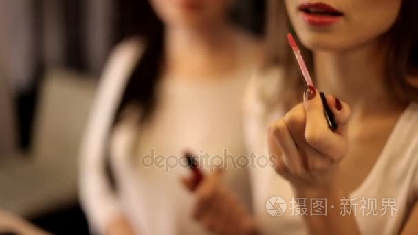 两个女人在镜子前用化妆品涂在脸上。化妆, 准备婚礼或庆典。两个女孩坐在化妆师的沙龙, 她是做时髦的做