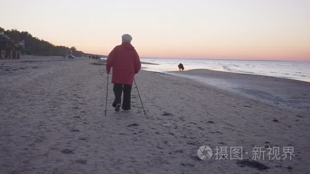 老妇人沿着海滨走着北欧的手杖视频