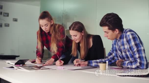 一群年轻的时髦人在现代办公室里一起工作。年轻的专业人士做素描坐在桌子上, 准备他们的新项目和喝咖啡在 slowmotion