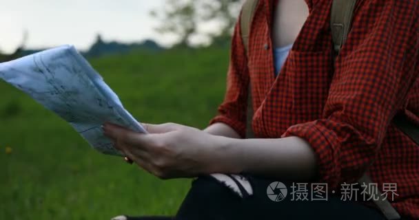 美丽的年轻旅游女孩与背包的关闭视图使用该区域的纸张地图。享受探险和旅行。背景山