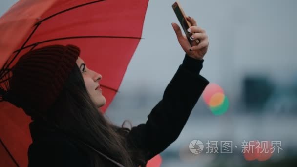 红色雨伞下的快乐女人制作手机照片