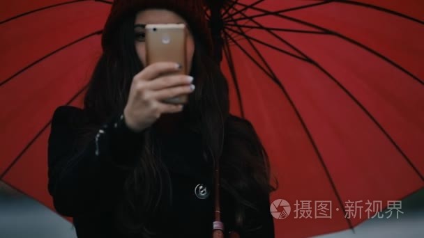 红色雨伞下的快乐女人制作手机照片