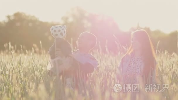 傍晚时分  一个三人的年轻家庭高高兴兴地从麦田里跳出来。在阳光的照射下  他们互相玩耍  互相拥抱。快乐的父亲和母亲