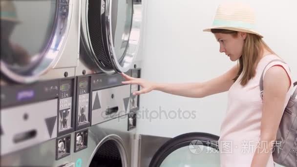 洗衣房里戴着帽子的年轻女人。阅读如何使用公共自助洗衣店洗衣服