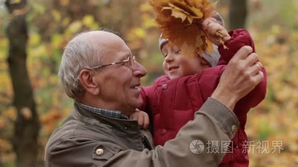 爷爷与蹒跚学步的男孩在秋天公园休息