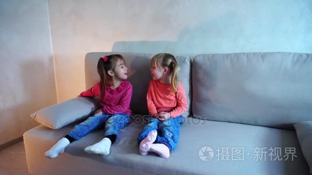 两个小女孩坐在沙发上玩耍  互相展示舌头