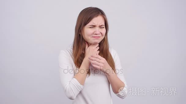 一个年轻的女人在灰色背景下喉咙痛短视频