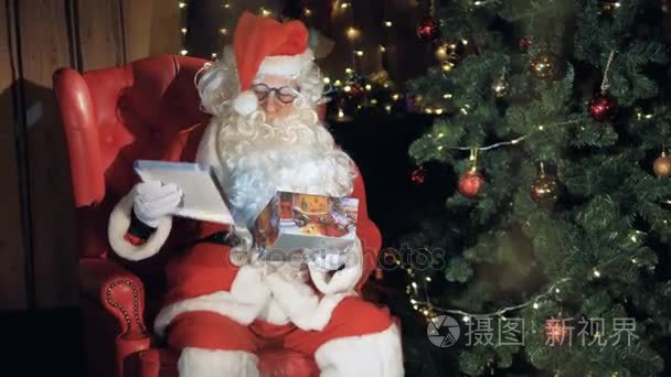 圣诞老人在圣诞树旁的椅子上包装礼物盒