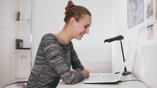 快乐的女实业家或秘书与笔记本电脑在办公室进行视频聊天。她挥舞着她的手  微笑着