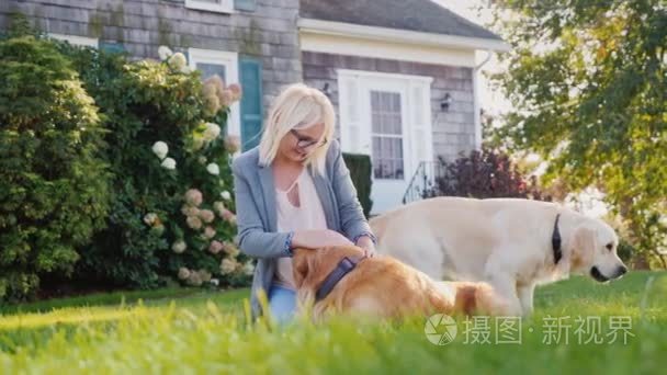 在房子附近的院子里玩两个金猎犬的女人