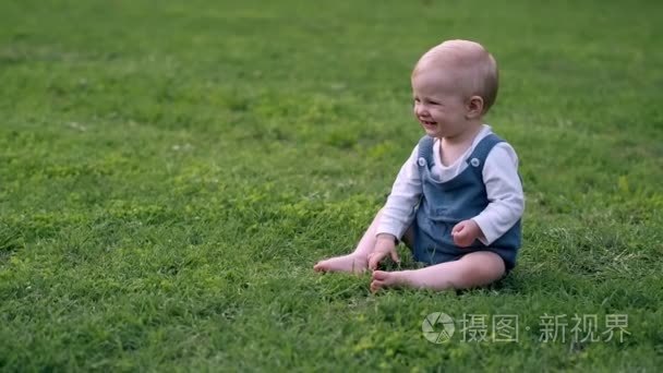 画像小女孩坐在草甸和撕下绿色草在夏天天