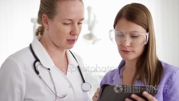 两位漂亮的女医生在病房里讨论平板电脑的事。医务人员工作