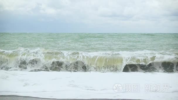 泡沫从波浪卷起卵石滩慢墨视频