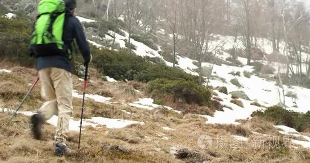 徒步旅行者背着背包走在雪地小路上。跟着前面真正的背包人成人徒步旅行或在秋季或冬季野外远足自然  恶劣的大雾天气. 4 k 视频