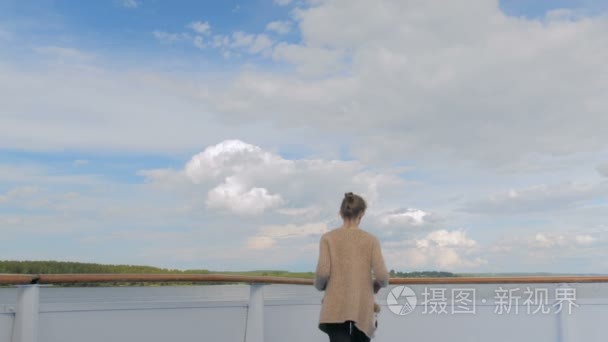 年轻女子站在邮轮甲板上, 看着河流和景观