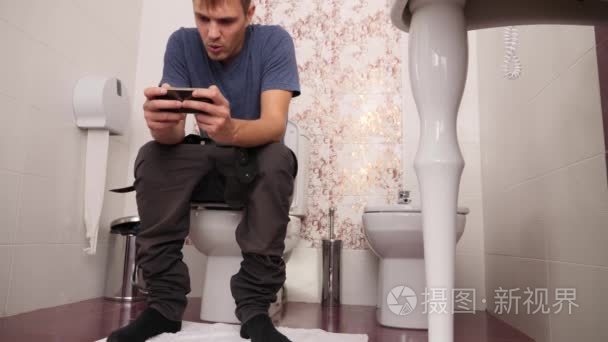 男人坐在马桶上, 看着手机.4k慢动作短视频