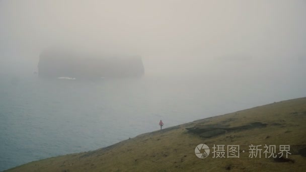 年轻的旅行者在海边的雾和探索海滩在阴天在冰岛附近的 Vestmannaeyjar