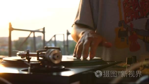 混合和刮  一个 Dj 的手在乙烯基和搅拌机旋钮。慢动作 120 fps。用万向节射击。日落