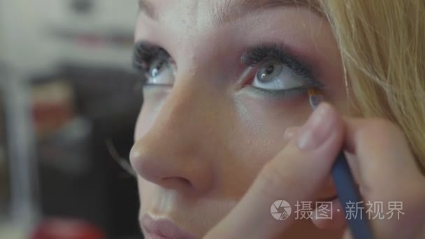 年轻化妆师在模特眼中应用化妆品