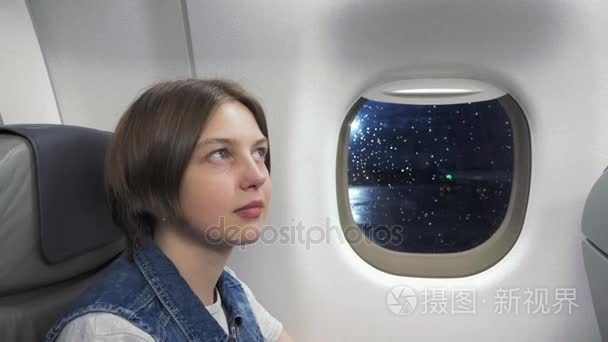 年轻女人从飞机的窗户看视频