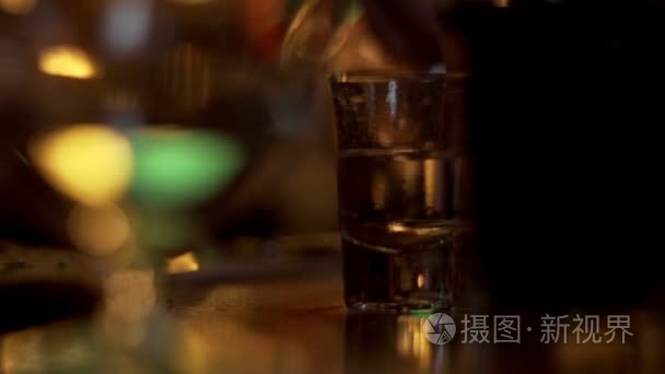 喝杯伏特加酒杯站在桌上的背景浇注男性手