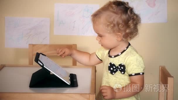 可爱的小女孩使用平板电脑坐近桌