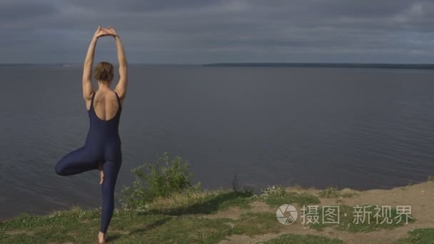 运动服的瑜伽妇女对湖的姿势视频