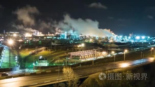 在夜间的道路附近的炼油厂与管道和蒸馏复合物。时间流逝