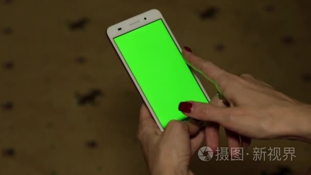 一个女人拿着一个绿色的屏幕智能手机