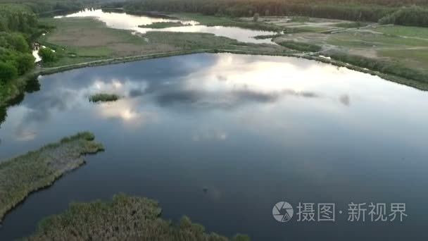 日落时飞越森林湖上空的无人驾驶飞机