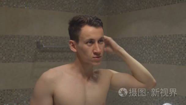 年轻有魅力的男人在酒店房间的浴室淋浴后直直的发型