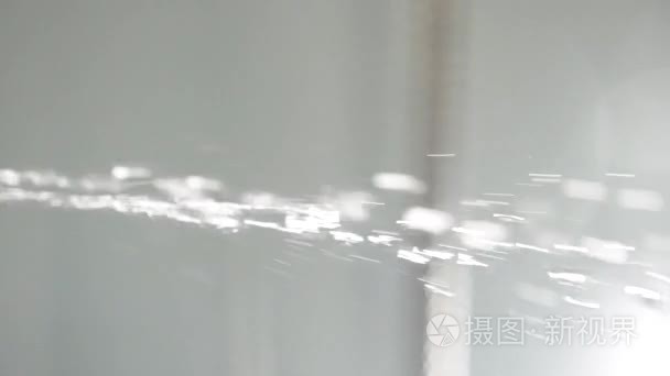 在白色背景下  浴室的淋浴喷头上有水滴。在白色的背景上溅水。下落的水下落