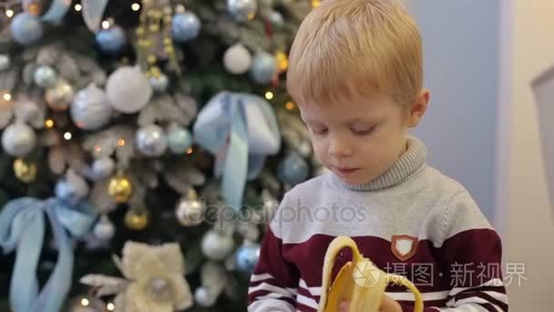 小孩子在圣诞树附近吃香蕉视频